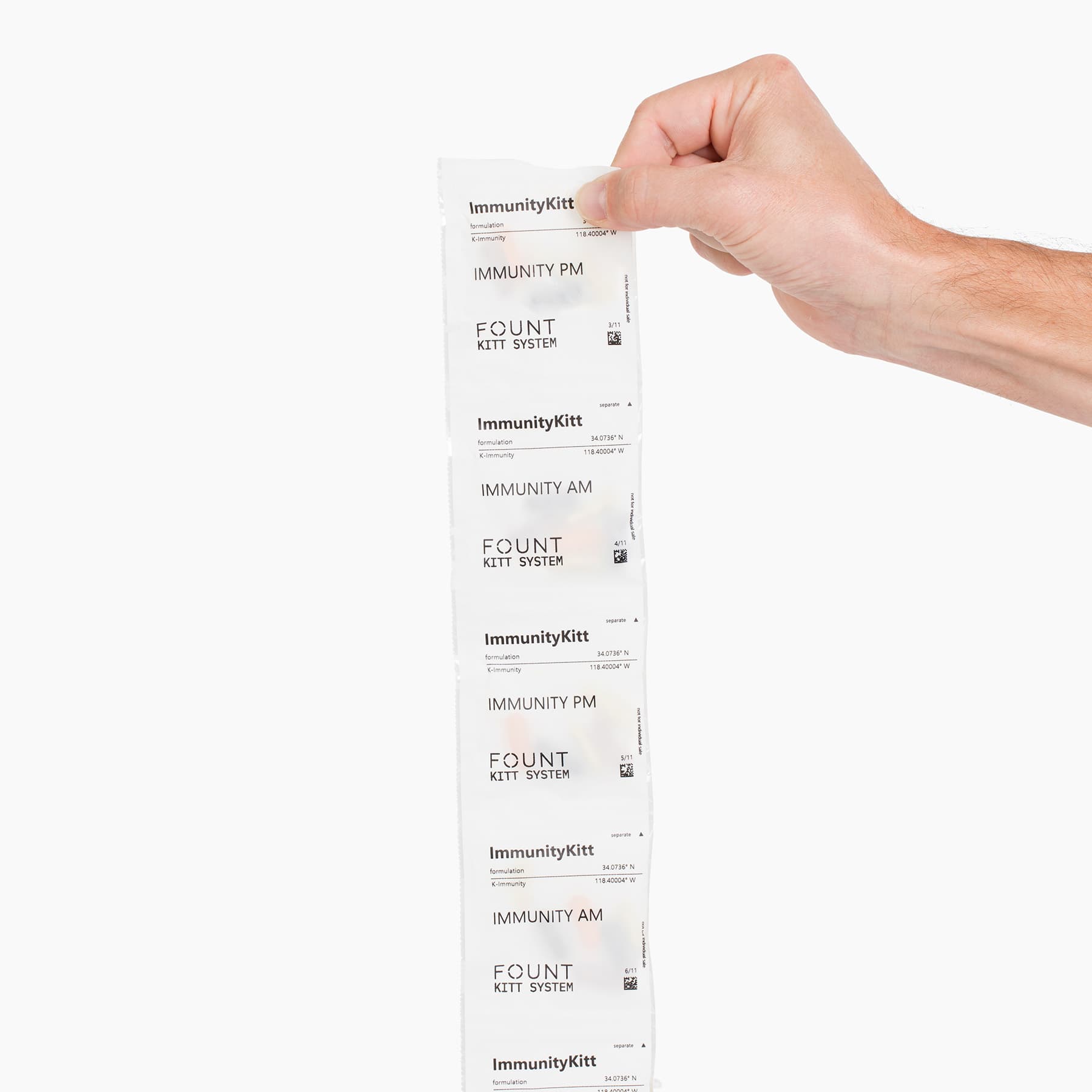 A hand holds a strip of supplements labeled IMMUNITYKITT by KITTS, designed to boost your immune system. The vertically arranged packets feature both Immunity AM and PM options, ideal for enhancing energy and mood. They stand out against a plain white background.